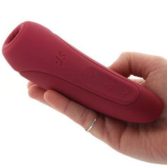 Hand holding the Satisfyer Curvy 1+ rose red silicone stimulator, showing its ergonomic curved shape