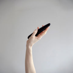 Hand holding a slim black obsidian crystal wand horizontally, showing its ergonomic length