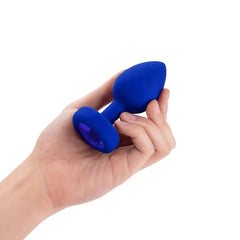 Hand holding small navy blue silicone jewel plug to show compact size and shape