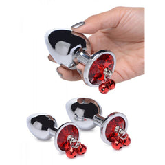 Hand holding small silver anal plug with red crystal base and decorative red bells