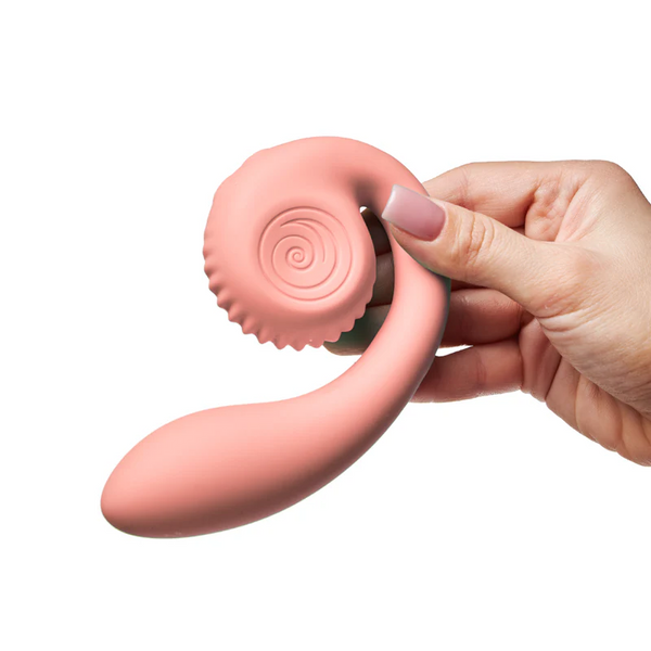 Hand holding the Snail GIZI vibrator showing soft peachy pink silicone texture and ergonomic curved form