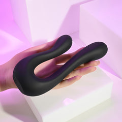 Hand holding The Swan black silicone dual vibrator to show flexible U-shaped form