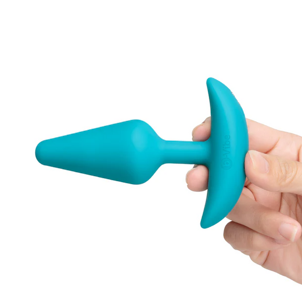 Hand holding teal silicone b-Vibe anal plug by its curved base to show compact size