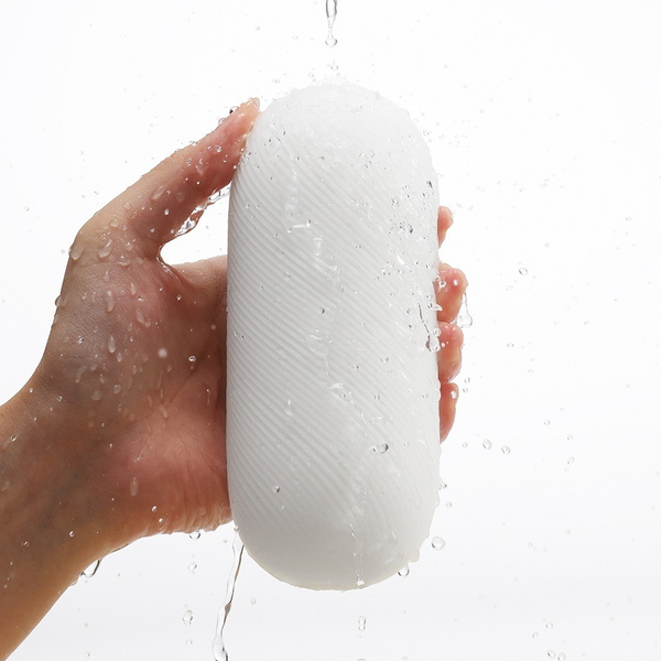 Hand holding Tenga 3DX ZEN under running water, showing waterproof washable design