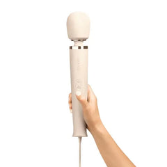 Hand holding upright Le Wand cream wand massager showing ergonomic handle and button panel