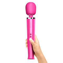 Hand holding upright magenta Le Wand massager showing ergonomic handle grip and controls