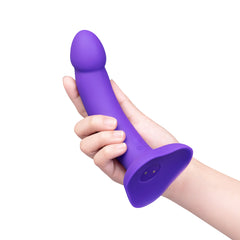 Hand holding upright purple silicone dildo to show length and ergonomic curved design