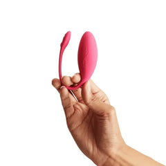 Hand holding the We-Vibe Jive upright, displaying its flexible curved silicone tail and egg shape