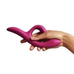 Hand holding We-Vibe Nova 2 fuchsia vibrator to show ergonomic size and flexible dual-arm design