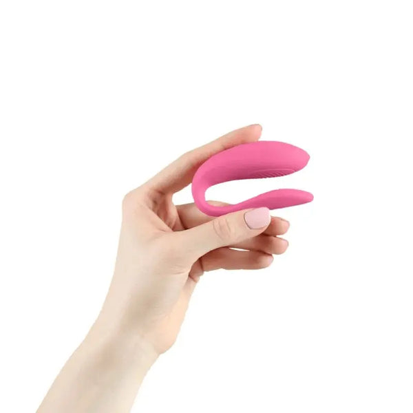 Hand holding the We-Vibe Sync Lite pink couple's vibrator to show compact, palm-fitting size