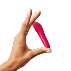 Hand holding We-Vibe Tango X cherry red bullet between thumb and forefinger, size reference