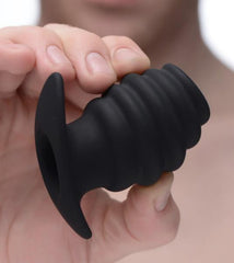 Hand holding XR LLC hollow tunnel plug showing open centre channel and ridged silicone texture