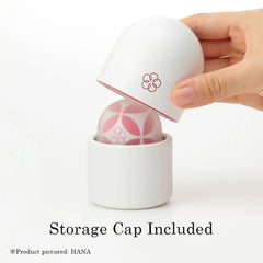 Hand lifting storage cap off Iroha Temari HANA, revealing dome-shaped silicone head nestled in cylindrical holder