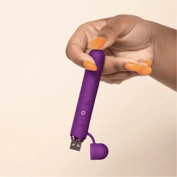 Hand with orange nails holding Le Wand Baton with USB port open, scale context
