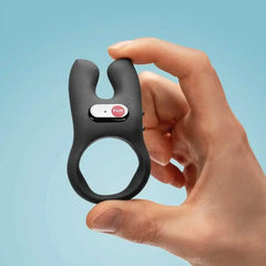 Close-up of hand pinching Fun Factory NŌS cock ring, highlighting flexible silicone band and button