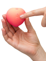Hand pressing the plus control button on the ROMP Pink Peach silicone stimulator