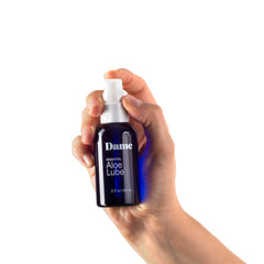 Hand pressing pump dispenser on Dame Aloe Lube bottle demonstrating one-hand ease of use
