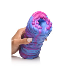 Hand squeezing Cyclone silicone stroker upright, showing flexible premium material and alien opening
