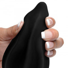 Hand squeezing flexible black silicone tip of the Assterisk ribbed anal plug showing soft bendable material