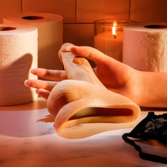 Hands demonstrating flexible soft TPE construction of Stand to Pee packer in warm bathroom setting