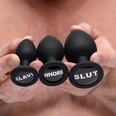 Hands holding all three Dirty Words silicone plugs together displaying engraved base details