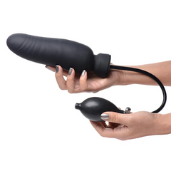Hands holding the Dick-Spand dildo body and separate inflation bulb, showing ridged texture detail