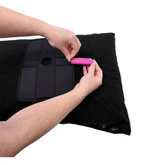 Hands inserting pink toy into attachment panel pocket on black waterproof pillow protector