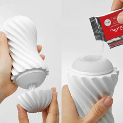 Hands opening Tenga Flex and applying lubricant packet into the soft flexible opening