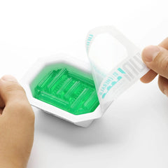 Hands peeling back sealed packaging to reveal green Emerald Uni sleeve inside gem-shaped tray