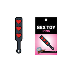 Heart paddle enamel pin beside its black and pink Sex Toy Pins branded card backing