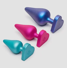 Heart-shaped bases of ROMP Luster plugs in blue, pink, and teal displayed at an angle