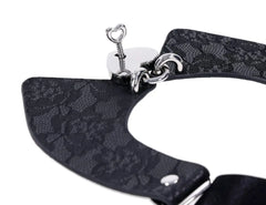 Close-up of heart-shaped key inserted into silver padlock on black lace collar fabric detail