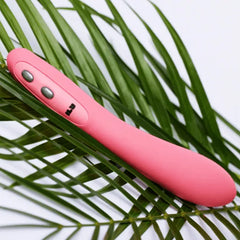 Je Joue ILY Wand pink vibrator resting on green palm leaves, buttons visible