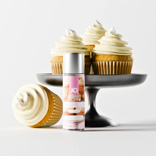 JO Bake Shoppe Frosted Cupcake water-based flavored lubricant 2 fl oz beside vanilla cupcakes on a cake stand