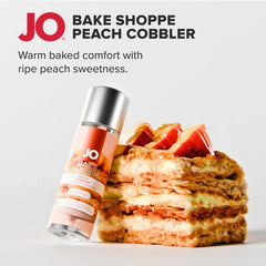 JO Bake Shoppe Peach Cobbler lubricant bottle leaning against a layered peach cobbler dessert stack
