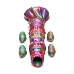 Larva Ovipositor Dildo laid flat beside four multicolor silicone eggs on white background