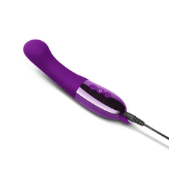 Le Wand Gee vibrator lying flat with USB charging cable connected to chrome base