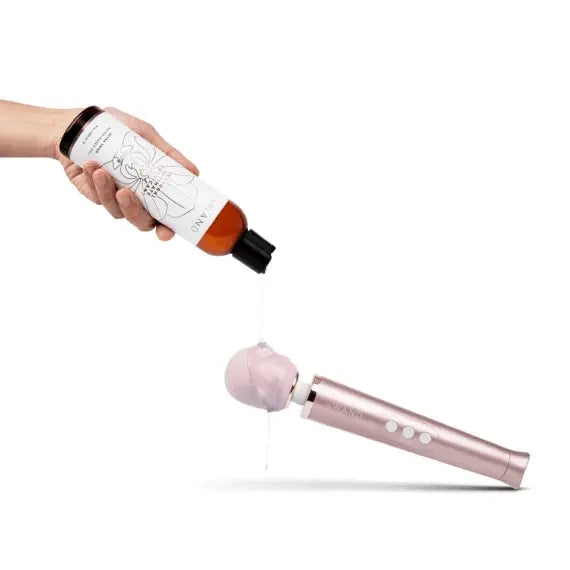 Le Wand lubricant being dispensed onto a rose gold wand massager head to demonstrate compatibility