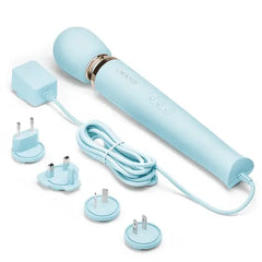 Le Wand massager displayed with four international plug adapters for global travel compatibility