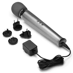 Le Wand massager laid beside power adapter and four international plug adapters for worldwide use