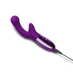 Le Wand XO purple vibrator lying flat with USB charging cable attached