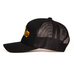 Left-side angle of black trucker cap highlighting gold embroidery detail on solid front panel
