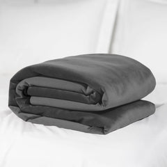 Liberator Fascinator Throw King folded on white bedding, highlighting the plush grey microvelvet surface