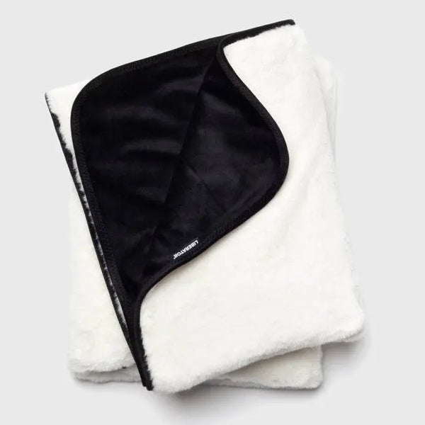 Liberator Fasinator Throw folded, showing white faux fur exterior and black velvet inner liner