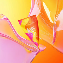 Love Me Tender coconut oil single-use sachet resting among flowing translucent glass-like forms