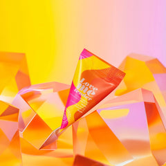Love Me Tender single-use oil cone packet balanced on crystal shapes with warm gradient backdrop