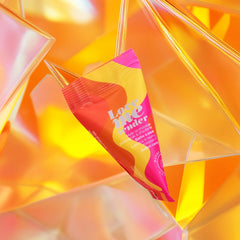 Love to Love Love Me Tender single-use oil sachet resting against warm golden reflective surface