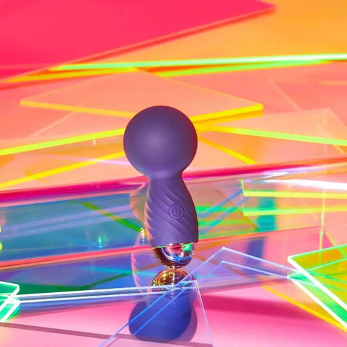 Love to Love Itsy Bitsy Tiny Wand in midnight indigo displayed among colorful acrylic panels