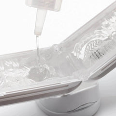 Lubricant flowing from nozzle into open ribbed clear sleeve resting on white display stand
