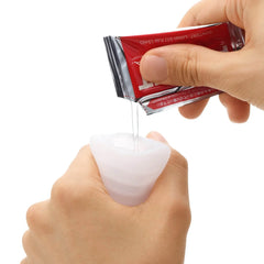 Lubricant sachet being poured into the soft opening of the Pocket Tenga sleeve before use